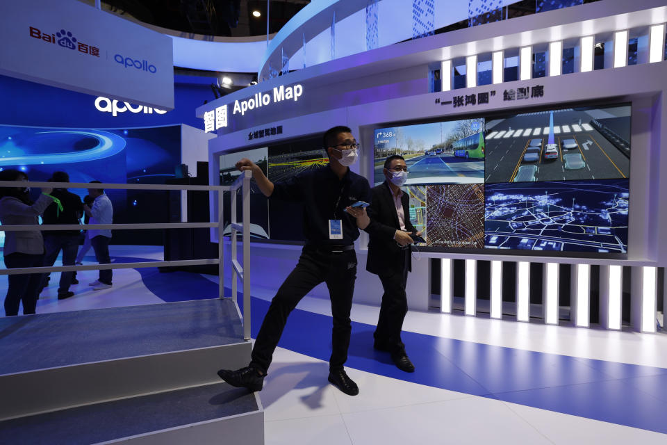 Visitors stand near the booth promoting the mapping service of Baidu's Apollo Map during the Shanghai Auto Show in Shanghai on Monday, April 19, 2021. Automakers are looking to China, their biggest market by sales volume and the first major economy to rebound from the pandemic, to revive sales and reverse multibillion-dollar losses. (AP Photo/Ng Han Guan)