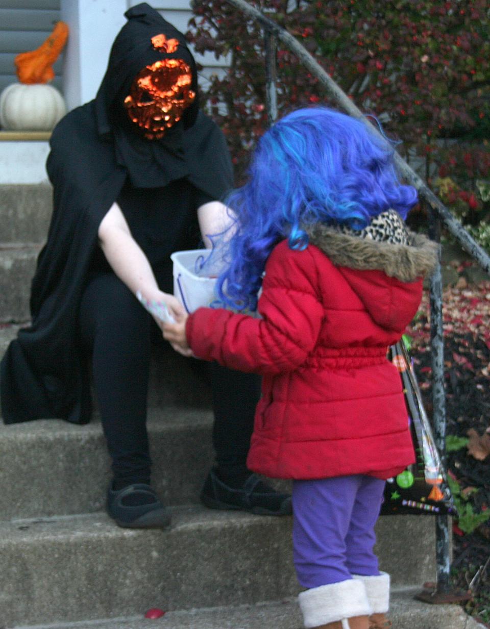 Lexy Hyatt offers candy to Ellissa Pasheilich in her Loudonville neighborhood during trick or treat in 2020.