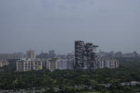 Explosives are detonated to demolish twin high-rise apartment towers in Noida, outskirts of New Delhi, India, Sunday, Aug. 28, 2022. The demolition was done after the country's top court declared them illegal for violating building norms. The 32-story and 29-story towers, constructed by a private builder were yet to be occupied and became India's tallest structures to be razed to the ground. (AP Photo/Altaf Qadri)