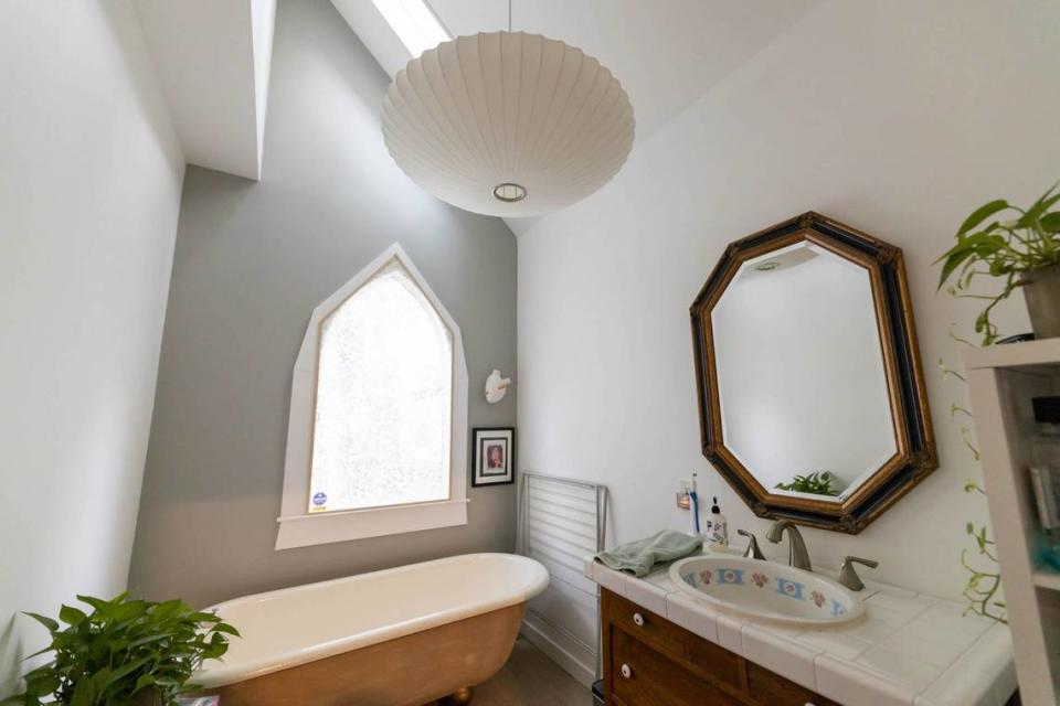 The bathroom of this Fourth Ward home has a modern lighting fixture to contrast with the claw-foot tub, decorative porcelain sink and uniquely shaped window. Oh, and plants.