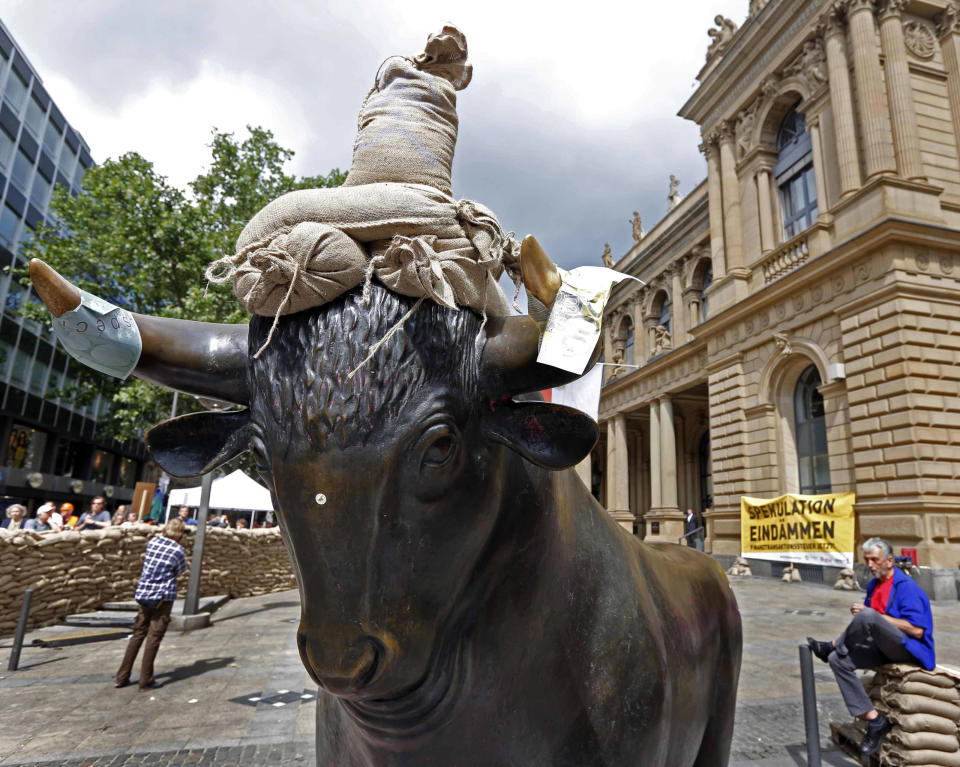 The sculpture of the bull is surrounded by a wall of sandbag at the Frankfurt stock exchange to demonstrate against the current financial policy in Frankfurt, central Germany, Sunday June 17, 2012. Poster at right reads: Stem Speculations Activists calling for a tax on financial transactions have erected a wall of sandbags outside the Frankfurt stock exchange. The anti-globalization group Attac said that about 200 people participated in Sunday’s action. Carrying placards with slogans such as “Stem Speculation” and “Financial transaction tax now,” they built the wall of sandbags around the statues of a bull and a bear symbols of optimistic and pessimistic markets that stand in front of the exchange building. White spot at the bull's nose is a sticker. (AP Photo/dapd/Mario Vedder)