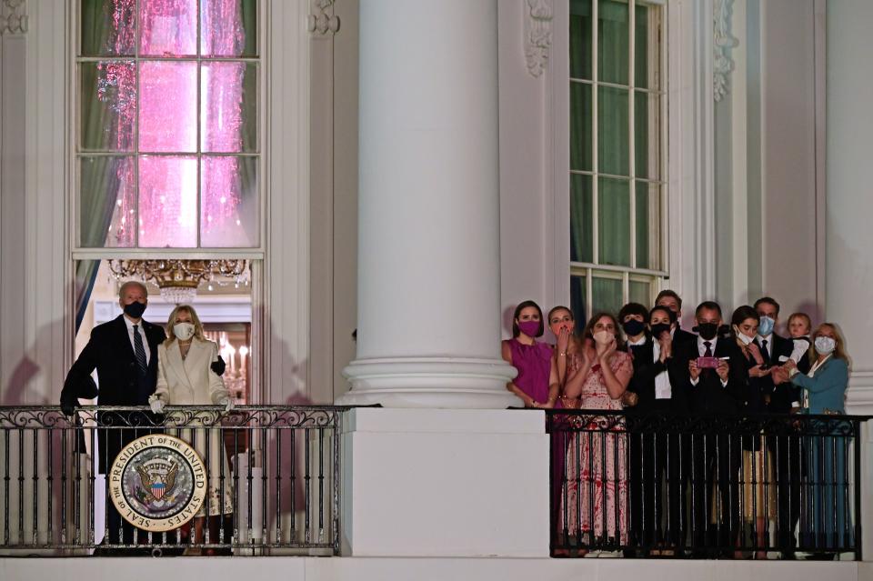 TOPSHOT - US President Joe Biden (L) and First Lady Jill Biden (2nd L) appear on the Blue Room Balcony as they and family members (R) watch fireworks from the White House in Washington, DC on January 20, 2021. (Photo by JIM WATSON / AFP) (Photo by JIM WATSON/AFP via Getty Images)