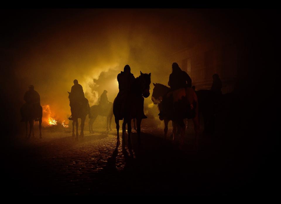 Revelers ride their horses near by bonfires in San Bartolome de Pinares, Spain, Monday, Jan. 16, 2012, in honor of Saint Anthony, the patron saint of animals. On the eve of Saint Anthony's Day, hundreds ride their horses trough the narrow cobblestone streets of the small village of San Bartolome during the 'Luminarias' a tradition that dates back 500 years and is meant to purify the animals with the smoke of the bonfires and protect them for the year to come. (Daniel Ochoa de Olza, AP)