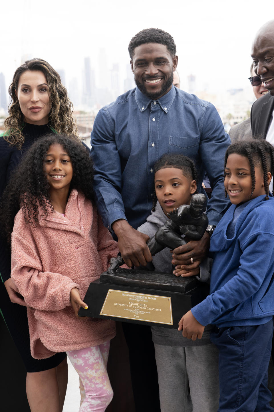 Former USC football player Reggie Bush poses with his family and his Heisman trophy after a news conference at the Los Angeles Memorial Coliseum, Thursday, April, 25, 2024, in Los Angeles. (AP Photo/Richard Vogel)