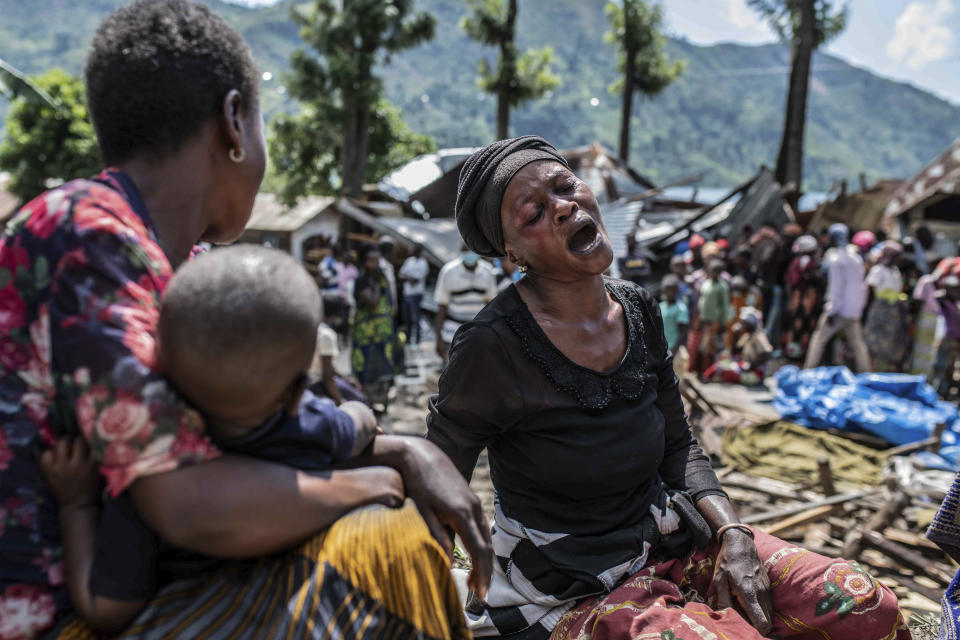 A woman reacts upon discovering that members of her family were killed, as volunteers nearby remove their bodies, in the village of Nyamukubi, South Kivu province, in Congo Saturday, May 6, 2023. The death toll from flash floods and landslides in eastern Congo has risen according to the governor and authorities in the country's South Kivu province. (AP Photo/Moses Sawasawa)
