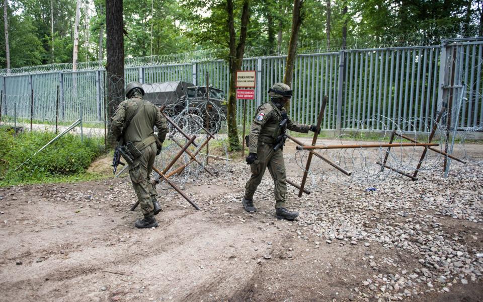 Polish soldiers patrol the border with Belarus along the border fence in the Bialowieza forest