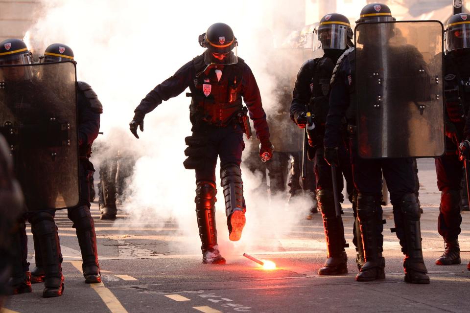 A French riot police officer kicks a flare during a demonstration against the pension overhauls, in Bordeaux, on December 5, 2019, as part of a national general strike.