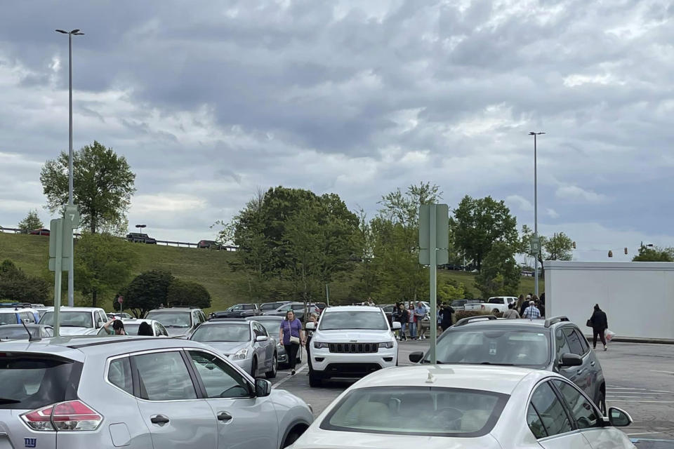 People walk through a parking lot at the Columbiana Centre mall in Columbia, S.C. on Saturday, April 16, 2022, as police investigate a shooting at the shopping center. (Justin Smith via AP)