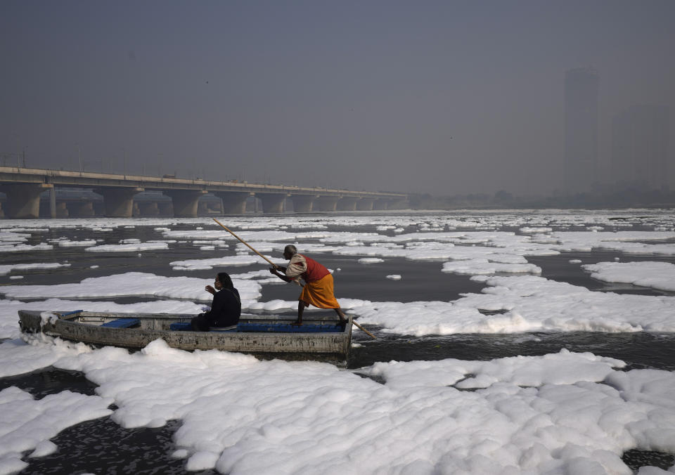 <p>A person takes a boat ride in the Yamuna River, covered by a chemical foam caused by industrial and domestic pollution as the skyline is enveloped in a blanket of toxic smog in New Delhi, India, Wednesday, Nov. 17, 2021. Schools were closed indefinitely and some coal-based power plants shut down as the Indian capital and neighboring states invoked harsh measures Wednesday to combat air pollution after an order from the federal environment ministry panel. (AP Photo/Manish Swarup)</p> 