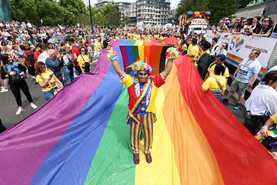 Mohammed Nazir from London, poses on a giant rainbow flag, during the Pride in London parade, in London, Saturday, July 2, 2022, marking the 50th Anniversary of the Pride movement in the UK. (James Manning/PA via AP)