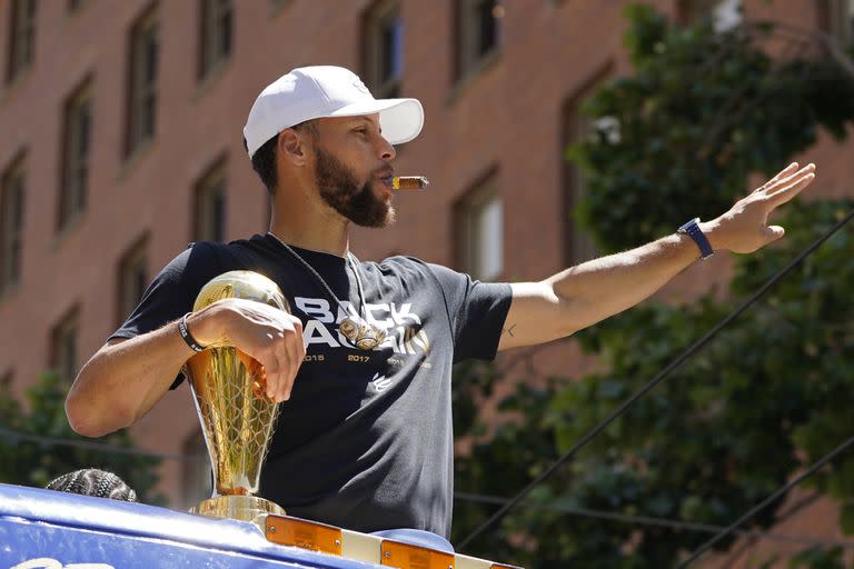 Stephen Curry fuma un puro y saluda a la afición en el desfile tras ganar el título de la NBA con los Warriors; la estrella de la NBA será el jugador mejor pago en la temporada 2022/23