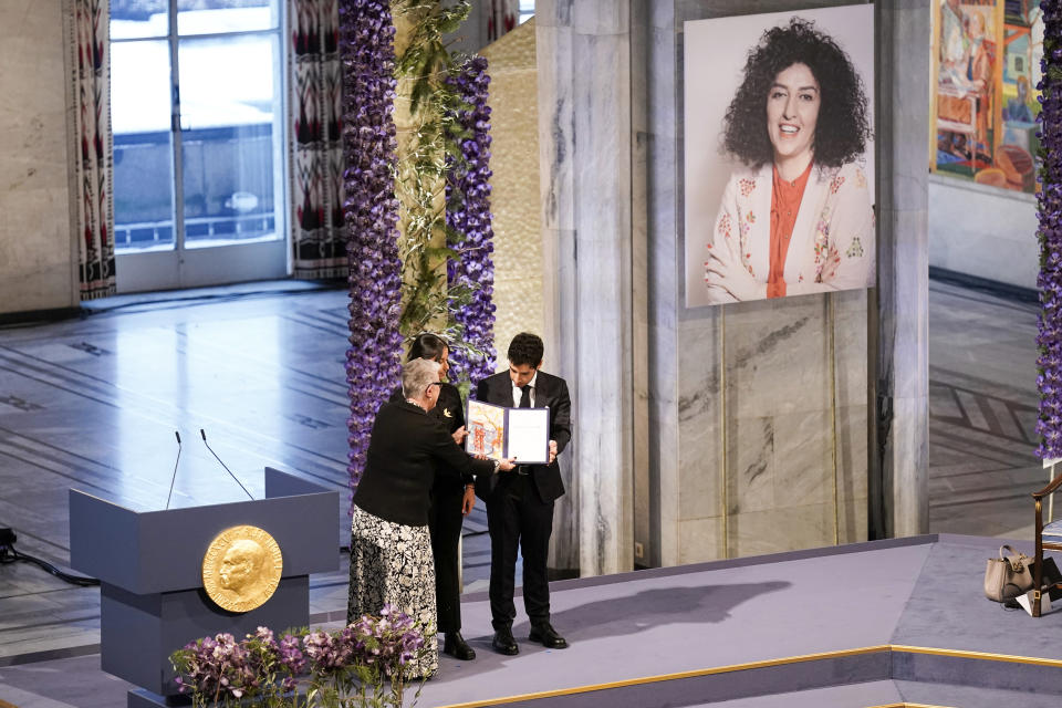 Leader of the Nobel Committee Berit Reiss-Andersen presents the Nobel Peace Prize for 2023 to Ali, right, and Kiana Rahmani, for their mother, imprisoned Iranian activist Narges Mohammadi, in Oslo City Hall, Oslo, Norway, Sunday, Dec. 10, 2023. Mohammadi is renowned for campaigning for women's rights and democracy in her country, as well as fighting against the death penalty. (Fredrik Varfjell/NTB via AP)