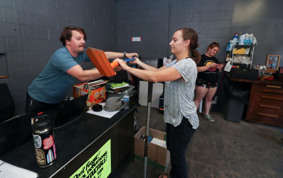 Emily Coleman, right, returns a rented trenching spade and tamper to Paul Faget at the Louisville Tool Library in Louisville, Ky. on July 13, 2022.  The library allows members to rent instead buying expensive tools they may need only once.