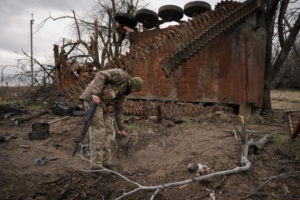 A Ukrainian serviceman pets a cat next to a destroyed Russian fighting vehicle after collecting parts and ammunition in the village of Andriivka, on April 6, 2022. Several buildings in the village were reduced to mounds of bricks and corrugated metal and residents are struggling without heat, electricity or cooking gas.