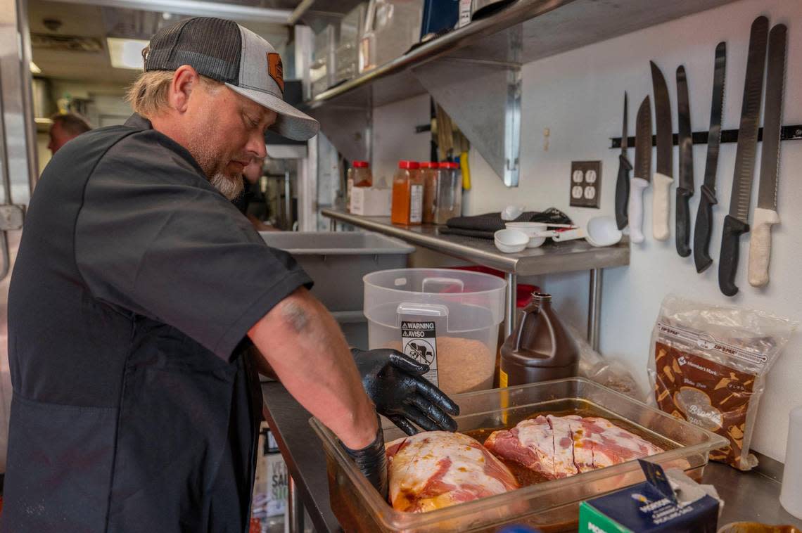 James Huey, co-owner at F325 BBQ, coats pork shoulder with a house-made marinade.