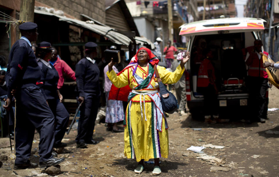 A follower of the Legio Maria church prays in the street next to a waiting ambulance, as rescuers nearby work to free a woman who had been trapped for six days in the rubble of a collapsed building, in the Huruma area of Nairobi, Kenya, May 5, 2016. After discovering the woman alive and conscious, rescuers administered an IV and oxygen but then had to work for a number of hours to free her from the rubble she was trapped in, before taking her away to hospital. (Ben Curtis/AP)