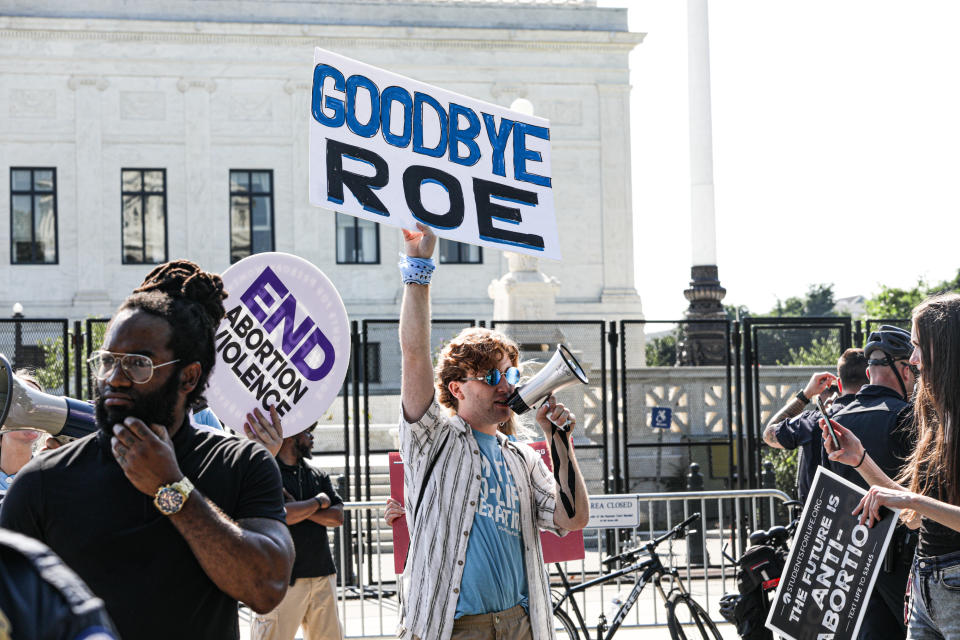 Anti-abortion protesters outside the Supreme Court. One man holds up a sign that reads: Goodbye, Roe.