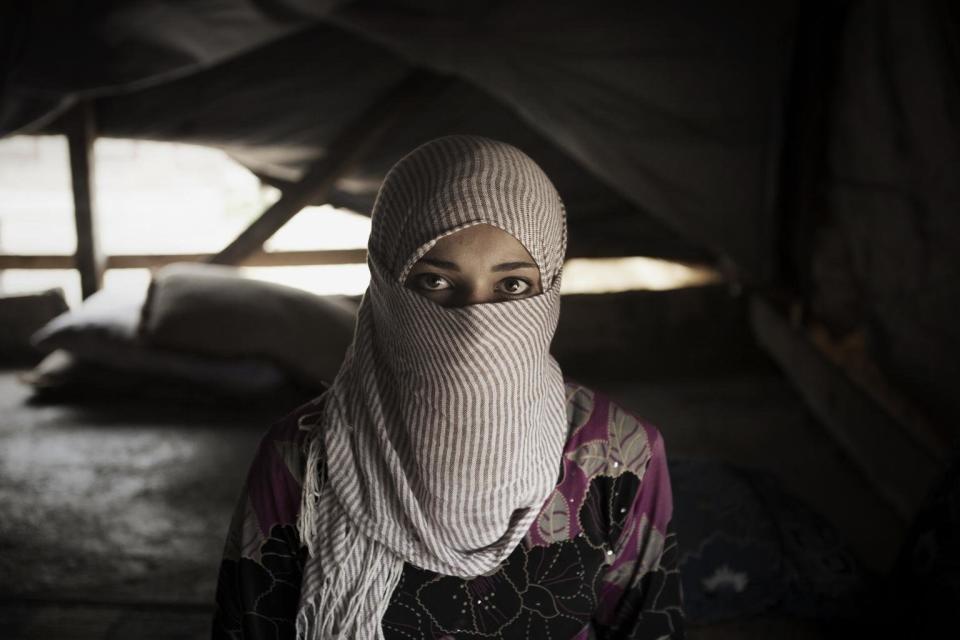 In Lebanon, Syrian refugee Waad, 13, stands inside her tent shelter. Waad, whose father forced her to marry a man she did not know, wants a divorce. Many Syrian refugees struggling to survive in Lebanon are marrying off their young daughters as a way of protecting their girls and to ease the family's financial burden.