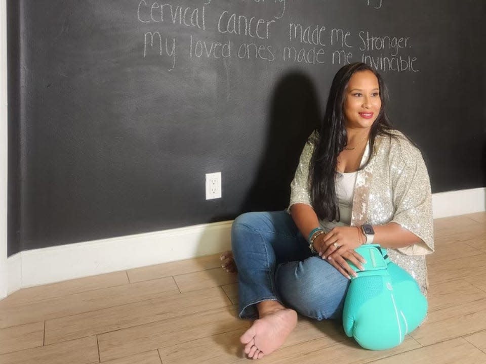 Avi Grant-Noonan in front of a blackboard detailing her treatment for cervical cancer.