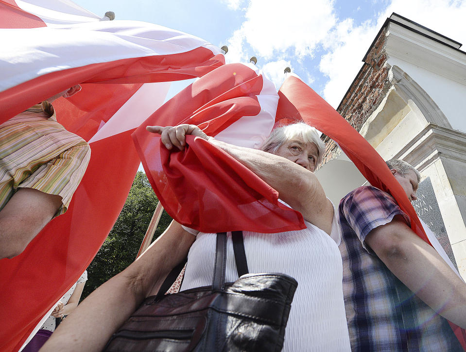 People hold Polish national flags as they attend an event by Polish officials and war veterans to pay tribute to a World War II-era underground force that collaborated with Nazi German forces toward the end of the war in their battle against the Communists, in Warsaw, Poland, Sunday, Aug. 11, 2019. President Andrzej Duda's official patronage and the presence of ruling party officials underlined the right-wing government's rehabilitation of a partisan unit that fought both Germans and Soviets and which is celebrated by the far right. (AP Photo/Czarek Sokolowski)