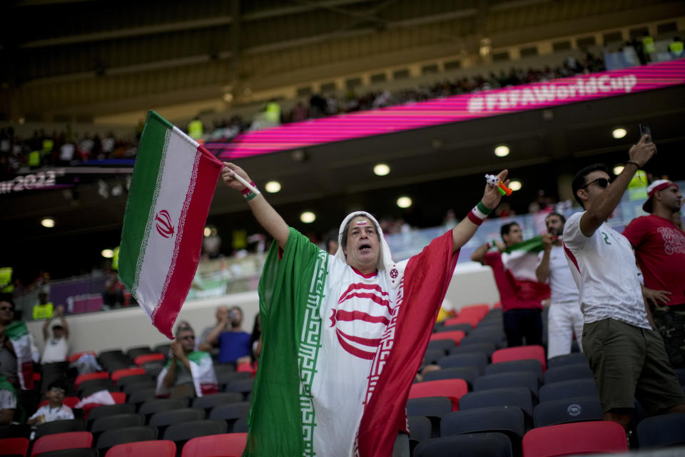 A soccer fan holds a flag from Iran prior to the World Cup group B soccer match between Wales and Iran, at the Ahmad Bin Ali Stadium in Al Rayyan , Qatar, Friday, Nov. 25, 2022. (AP Photo/Francisco Seco)