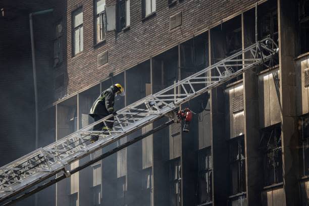 A firefighter climbs a ladder as they extinguish a fire in an apartment block in Johannesburg on 31 August 2023 (AFP via Getty Images)
