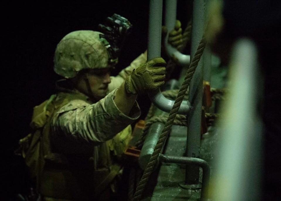 a marine climbs a ladder aboard a vessel