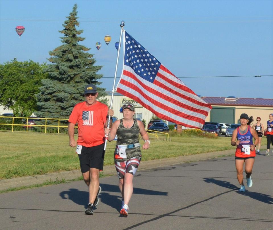 Greg Hacke, left, and Bernice Hacke, from Terrytown, New York run in the 2022 Battle Creek Half Marathon & 5K on Saturday and have carried the flag and competed in the event every year since the inaugural race.