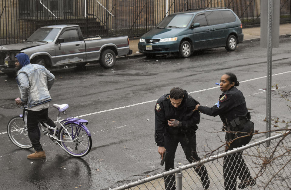 In this Dec. 10, 2019 photo, Jersey City police Sgt. Marjorie Jordan, right, helps fellow officer Raymond Sanchez to safety after he was shot during a gunfight that left multiple dead in Jersey City, N.J. The two killers were armed with a variety of weapons, including an AR-15-style rifle and a shotgun that they were wielding when they stormed into a store in an attack that left the scene littered with several hundred shell casings, broken glass and a community in mourning. Despite years of New Jersey officials focusing on the problems of crime guns coming into the state, Tuesday's shooting shows efforts are falling short. (Justin Moreau via AP)