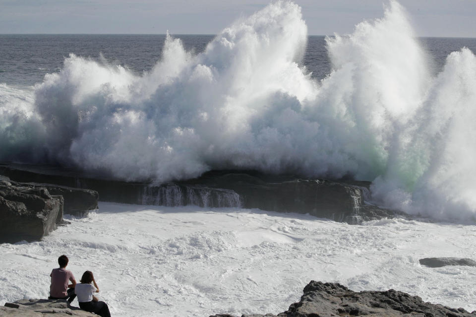 A couple watches waves hitting a coast of Shirahara town, Wakayama prefecture, central Japan, Monday, Sept. 3, 2018. Powerful Typhoon Jebi is approaching Japan's Pacific coast and forecast to bring heavy rain and high winds to much of the country.(Yosuke Mizuno/Kyodo News via AP)