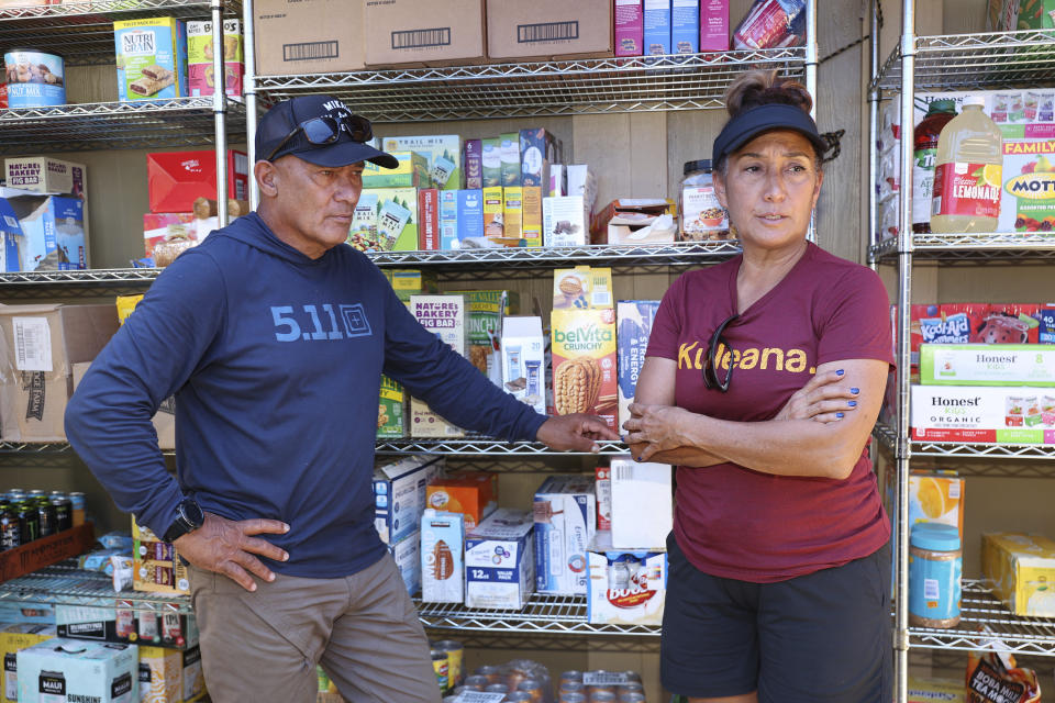 Archie Kalepa, left, and Alicia Kalepa stand outside their home that has become a fire-relief distribution hub in Lahaina, Hawaii, on Friday, Sept. 1, 2023. The Kalepas live in a Hawaiian Homestead community that lost only two out of 104 houses in a deadly August blaze. (AP Photo/Marco Garcia)