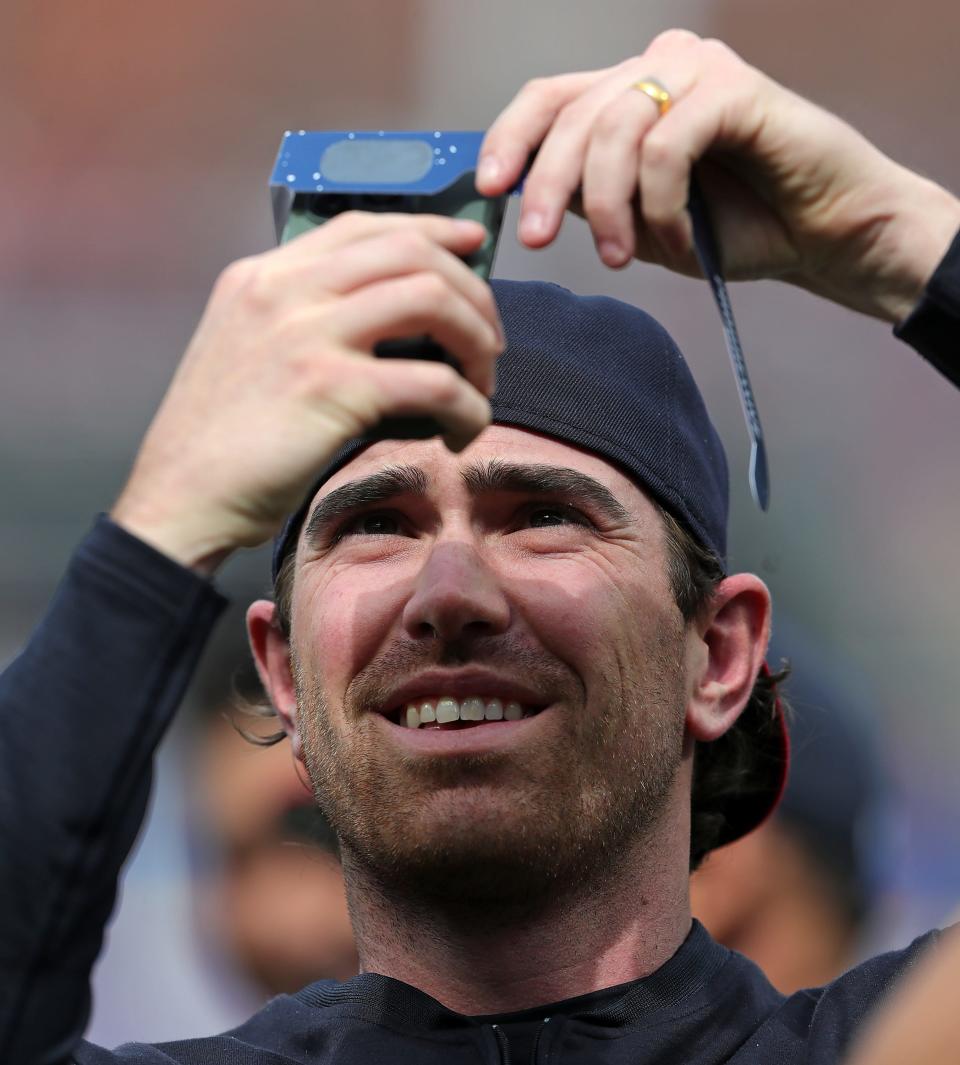 Cleveland Guardians pitcher Shane Bieber (57) takes a photo of the solar eclipse before the Cleveland GuardiansÕ home opener against the Chicago White Sox, Monday, April 8, 2024, in Cleveland, Ohio.
