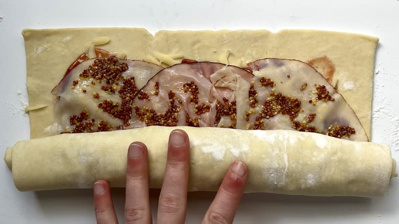 hand rolling up puff pastry