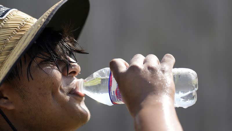 Carlos Rodriguez drinks water while taking a break from digging fence post holes Tuesday, June 27, 2023, in Houston. Meteorologists say scorching temperatures brought on by a heat dome have taxed the Texas power grid and threaten to bring record highs to the state.