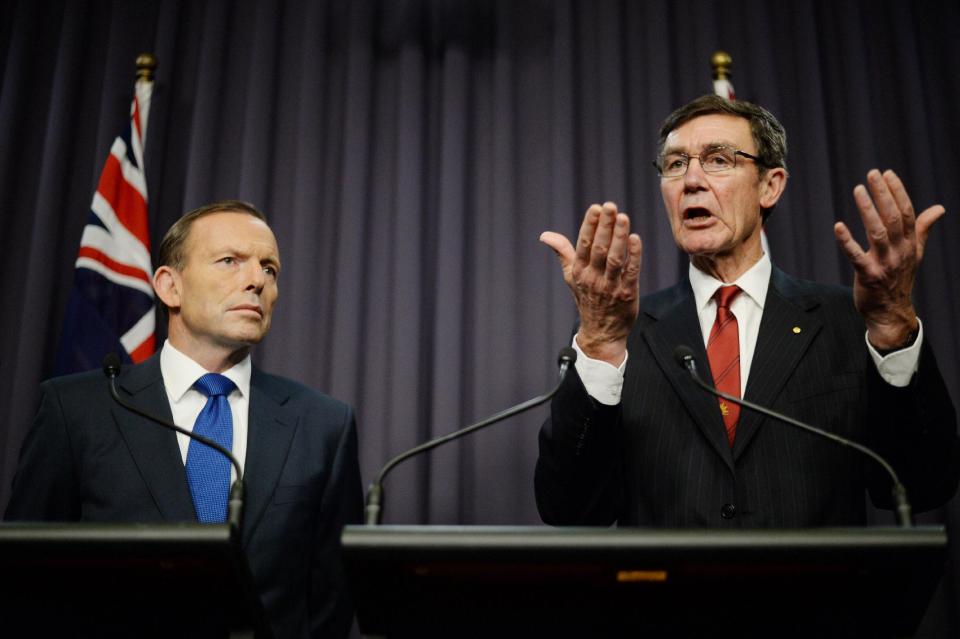 Prime Minister Tony Abbott, left, looks on as retired Chief Air Marshall Angus Houston, the head of the Joint Agency Coordination Centre, speaks to the media during a press conference at Parliament House in Canberra, Monday, April 28, 2014. Abbott and Houston announced Monday that the underwater hunt for the missing Malaysia Airlines jet will be expanded to include a massive swath of ocean floor that may take up to eight months to thoroughly search. (AP Photo/AAP Image, Lukas Coch) AUSTRALIA OUT, NEW ZEALAND OUT, PAPUA NEW GUINEA OUT, SOUTH PACIFIC OUT, NO SALES, NO ARCHIVES