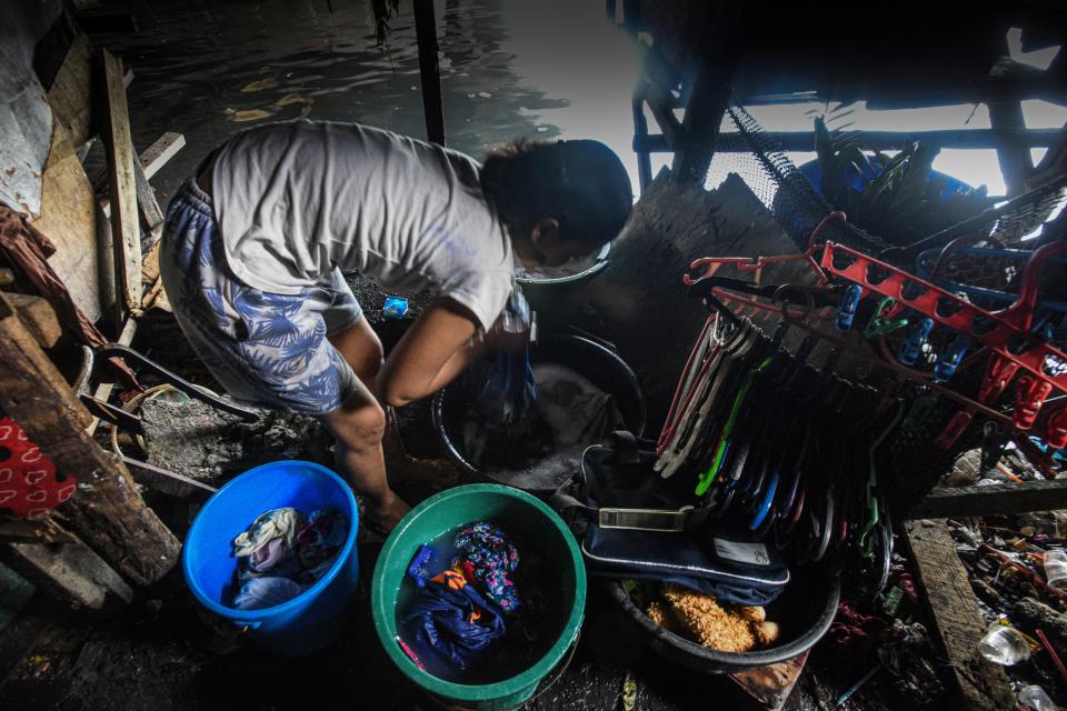This photo taken on March 18, 2020 shows a mother washing laundry outside her home along the river in Manila. - Asian nations have imposed increasingly heavy measures to fight the outbreak of the COVID-19 coronavirus, the Philippines has ordered half its population of some 110 million to stay home. (Photo by Maria TAN / AFP) / TO GO WITH Health-virus-Philippines-poverty,FOCUS by Joshua Melvin and Ron Lopez (Photo by MARIA TAN/AFP via Getty Images)