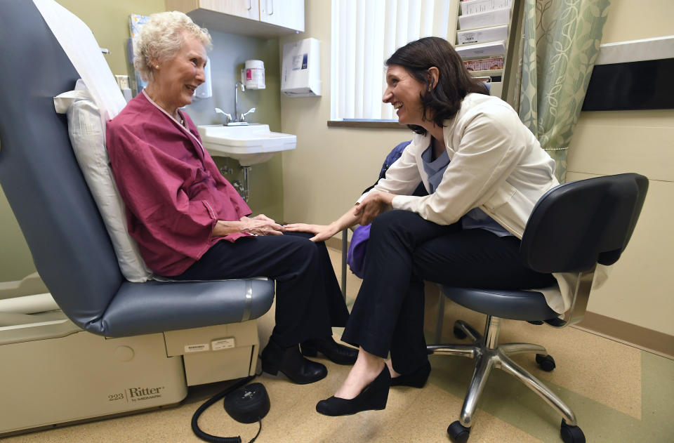 In this Monday, March 4, 2019 photo, Dr. Allison Magnuson, left, speaks with patient Nancy Simpson at the Pluta Cancer Center in Rochester, N.Y. Before she could start breast cancer treatment, Simpson, 80, had to walk in a straight line, count backward from 20 and repeat a silly phrase. It was part of a special kind of medical fitness test for older patients. (AP Photo/Adrian Kraus)