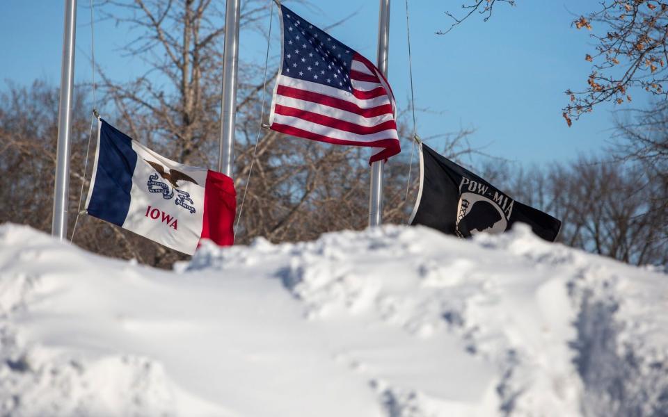 Flags surrounded by snow piles during a winter storm ahead of the Iowa caucus in Adel, Iowa, US,