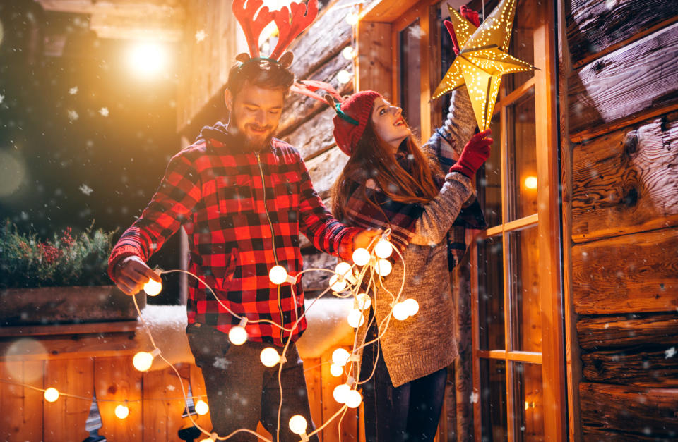 Couple putting up Christmas decorations. (Getty Images)