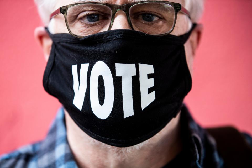 John Moran poses for a photo while wearing a mask that reads "VOTE" after casting a ballot at a polling station at Miette Patisserie on Nov. 3, 2020, in San Francisco.