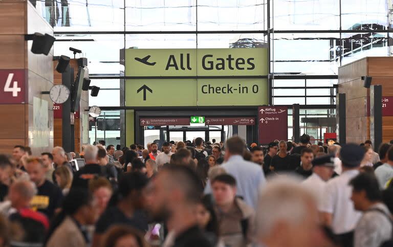 Pasajeros hacen cola para las salidas en el aeropuerto BER Berlín-Brandenburgo en Schoenefeld, después de que los vuelos se suspendieran temporalmente en el aeropuerto debido a la falla global