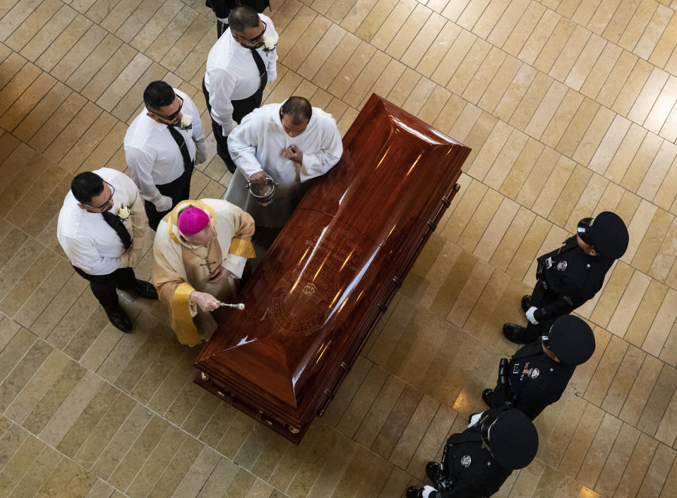 Archbishop Jose Gomez sprinkles holy water on casket as funeral mass for slain Los Angeles Police Department officer Juan Diaz gets underway at the Cathedral of Our Lady of the Angels in Los Angeles, Calif., on Monday, Aug. 12, 2019. (Brian van der Brug/Los Angeles Times via AP, Pool)