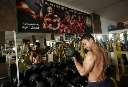 A bodybuilder exercises after having his back painted with Arabic letters by Palestinian artist Bilal Khaled in a gym in Gaza City April 12, 2016. REUTERS/Mohammed Salem