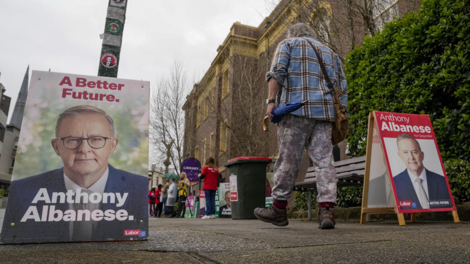 A voter walks past billboards with photos of Labor leader Anthony Albanese outside a pre-polling booth in Sydney, Australia, Friday, May 20, 2022. The son of a single mother who raised him on a pension, Anthony Albanese had a humble start to life for a politician who could become Australia's next prime minister(AP Photo/Mark Baker)