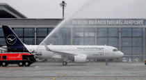 The airport fire brigade sprays water onto a 'Lufthansa' ariplane that is parked in front of Terminal 1 after its arrival at the new Berlin-Brandenburg-Airport 'Willy Brandt' in Berlin, Germany, Saturday, Oct. 31, 2020. Berlin's new airport opens after years of delays and cost overruns. (AP Photo/Michael Sohn)