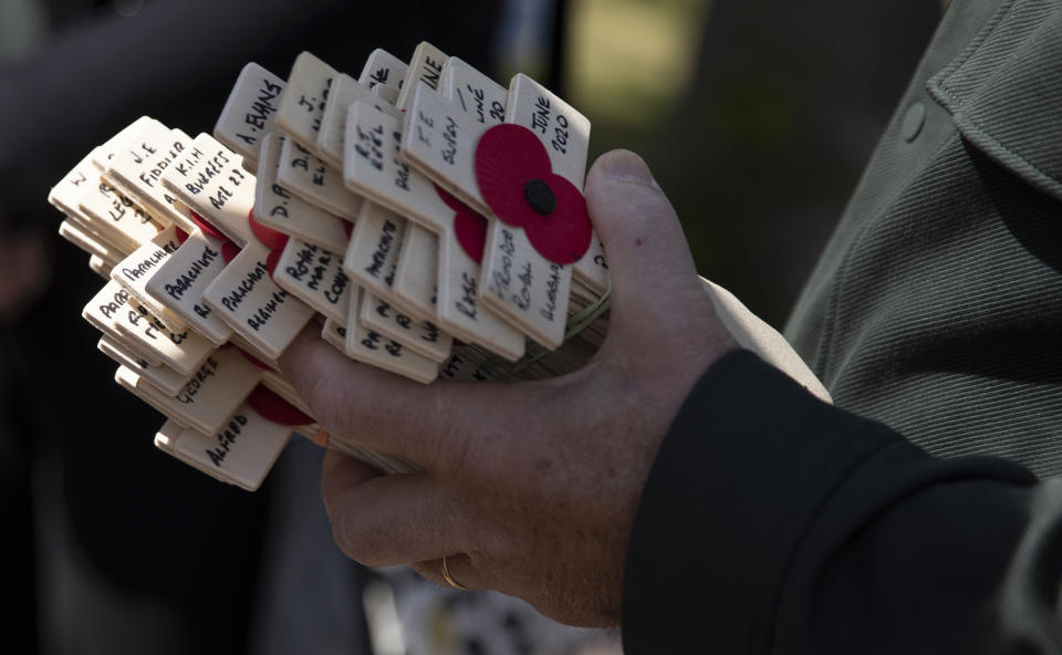 Wooden crosses with names of WWII dead are held prior to being laid for the Portsmouth Trust group by British expatriate Steven Oldrid during D-Day ceremonies at the local war cemetery in Benouville, Normandy, France on Saturday, June 6, 2020. Due to coronavirus measures many relatives and veterans will not make this years 76th anniversary of D-Day. Oldrid will be bringing it to them virtually as he places wreaths and crosses for families and posts the moments on his facebook page. (AP Photo/Virginia Mayo)