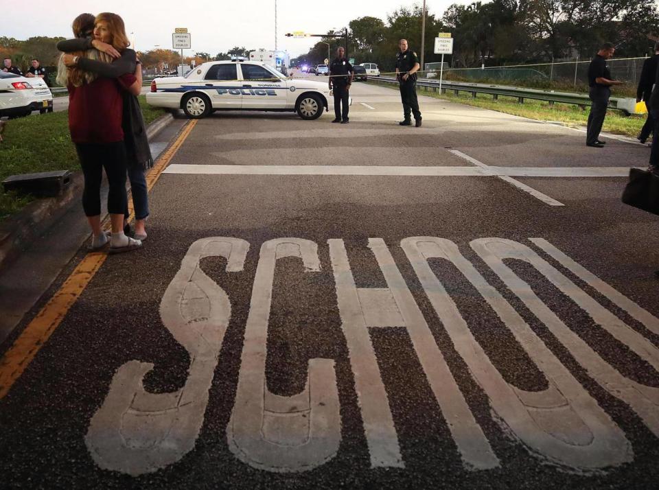 Two young women hug at a police checkpoint near the Marjory Stoneman Douglas High School where 17 people were killed by a gunman on 15 February 2018 in Parkland, Florida. (Getty)