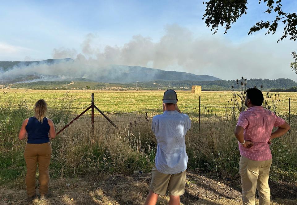 People watch a wildfire burn in the Coburg Hills east of the freeway from a rest area along Interstate 5 north of Eugene.