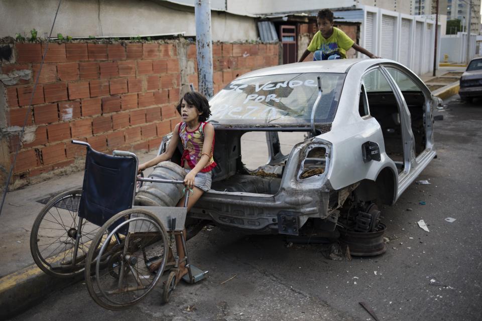 In this Nov. 14, 2019 photo, Ladymar uses her grandmother's wheelchair as a makeshift dolly to transport her water bottle water, in Maracaibo, Venezuela. Opposition leader Juan Guaido, who seeks to oust President Nicolas Maduro, has urged Venezuelans to take to the streets, trying to reignite a movement started early this year. However, few in Maracaibo have responded, despite it being a city hard hit by crisis. (AP Photo/Rodrigo Abd)