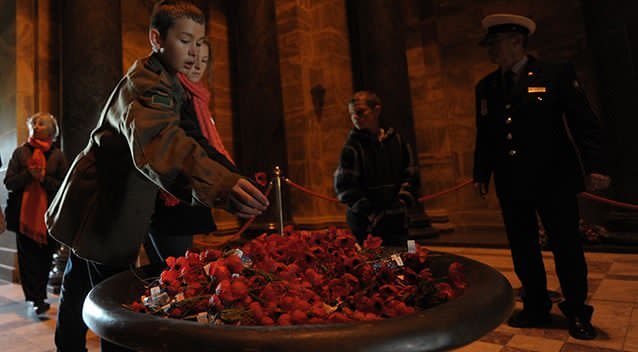 A young boy places a poppy into a memorial cauldron at the Shrine of Remembrance during the ANZAC Day dawn service in Melbourne, Friday, April 25, 2014. Photo: AAP
